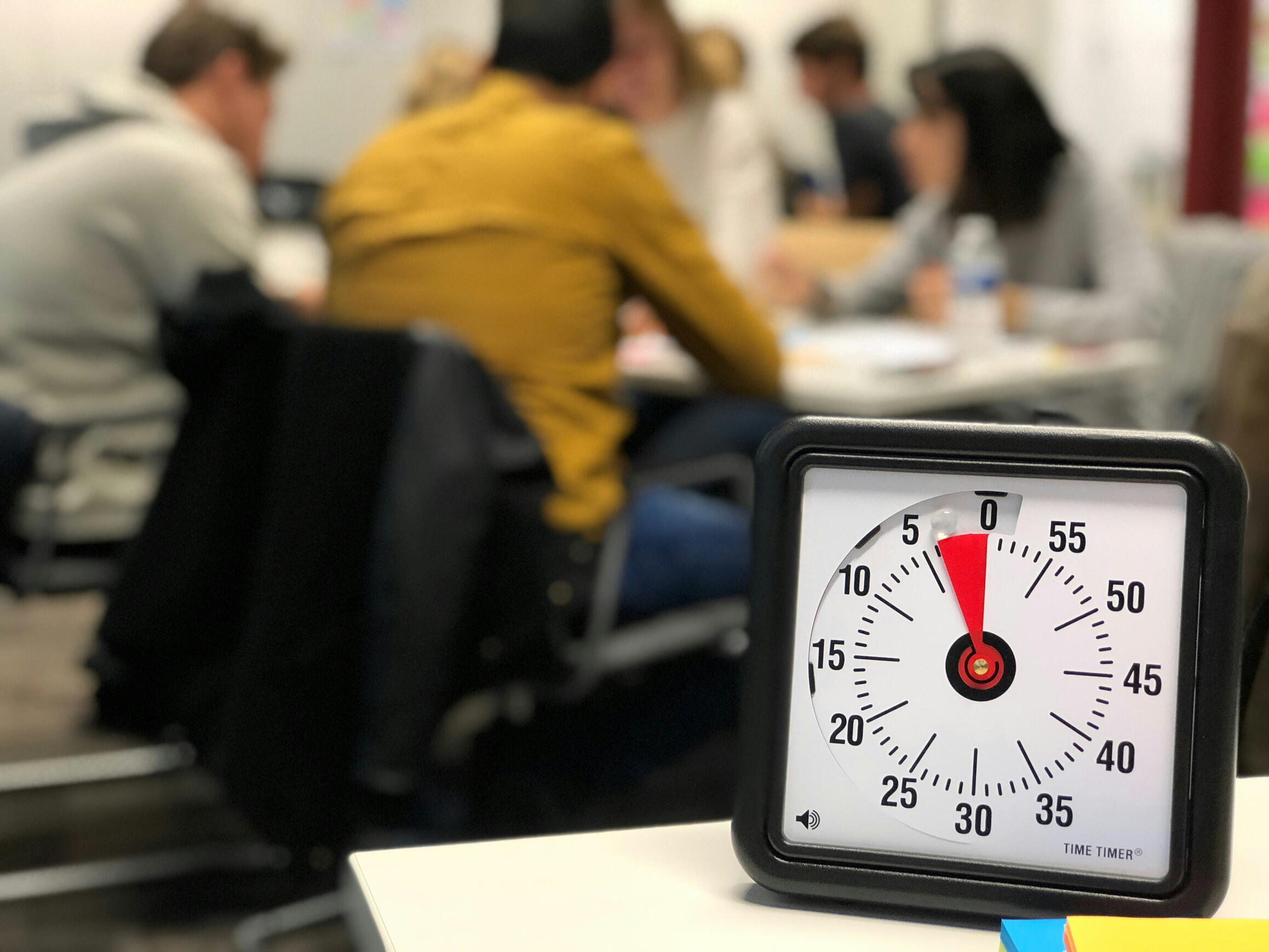 5 minutes left A timer clock showing 5 minutes left and people sitting at a table talking ni the background